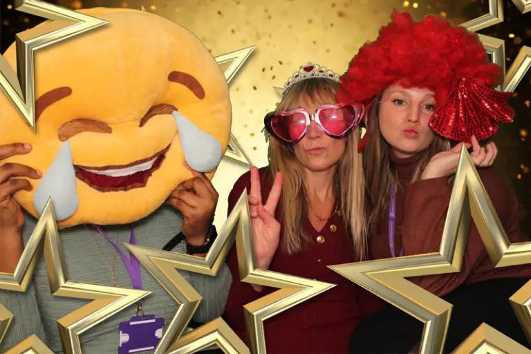 women holding a giant laughing emoji pillow in a MagicPix photo booth.